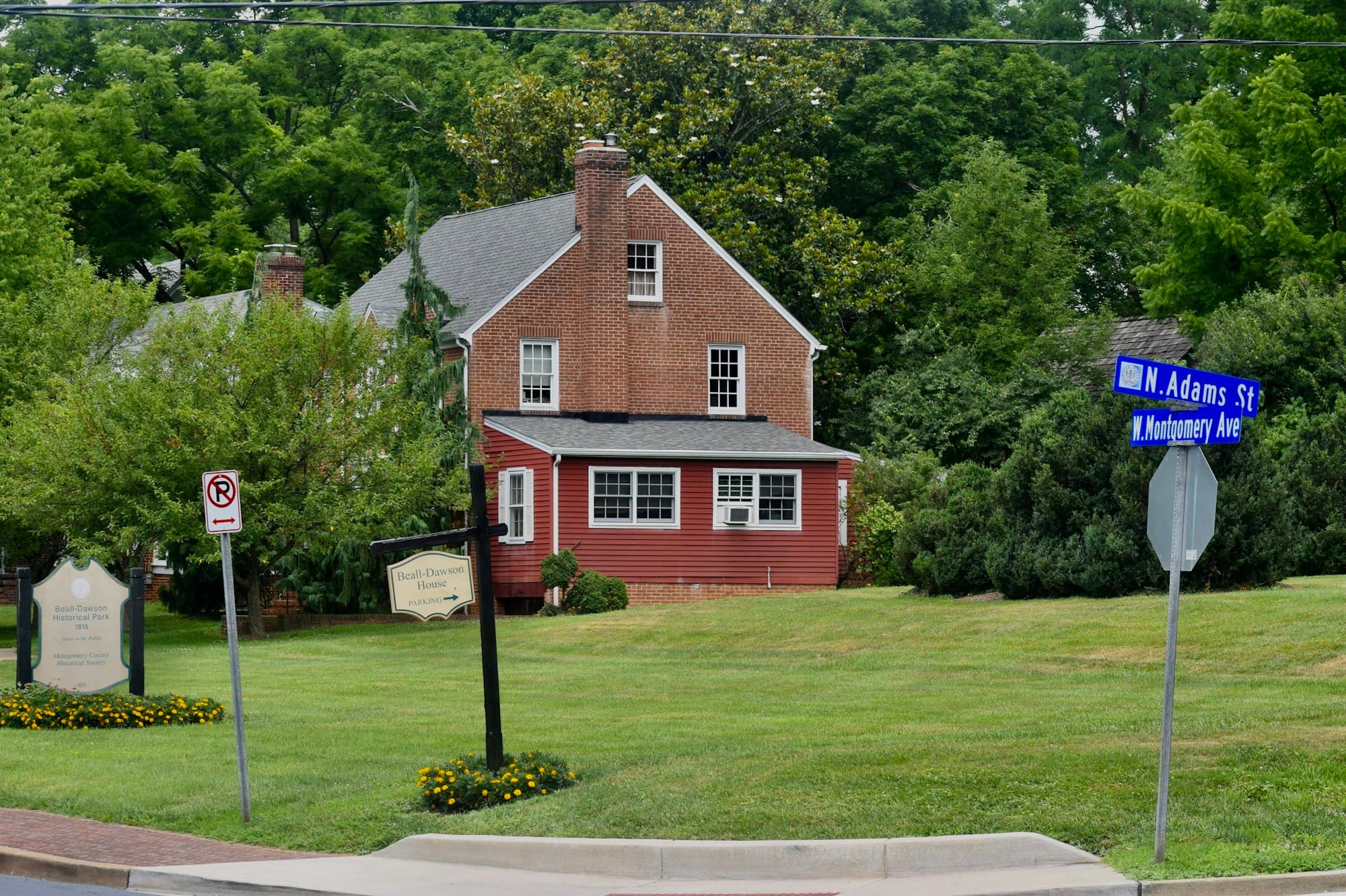 A red brick house on a corner lot with a blue street sign in Rockville, Maryland